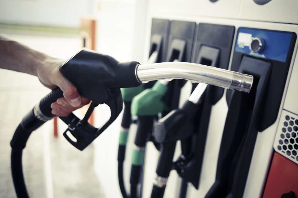 Hand removes gas nozzle from pump at a gas station.