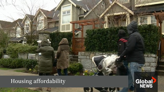 A group of people walks past a row of houses.